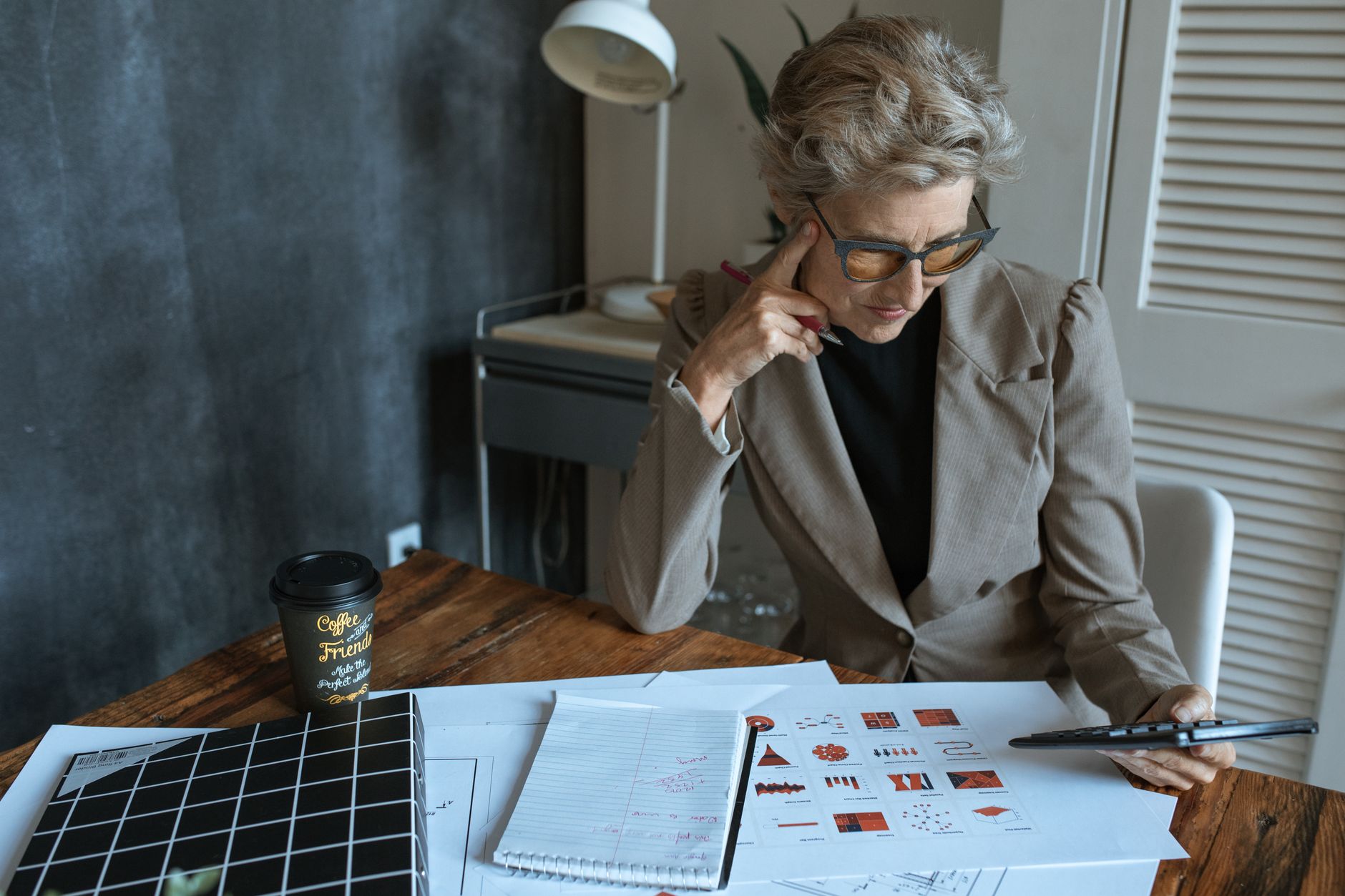 Vrouw die geconcentreerd documenten doorneemt aan een bureau in een thuiskantoor.