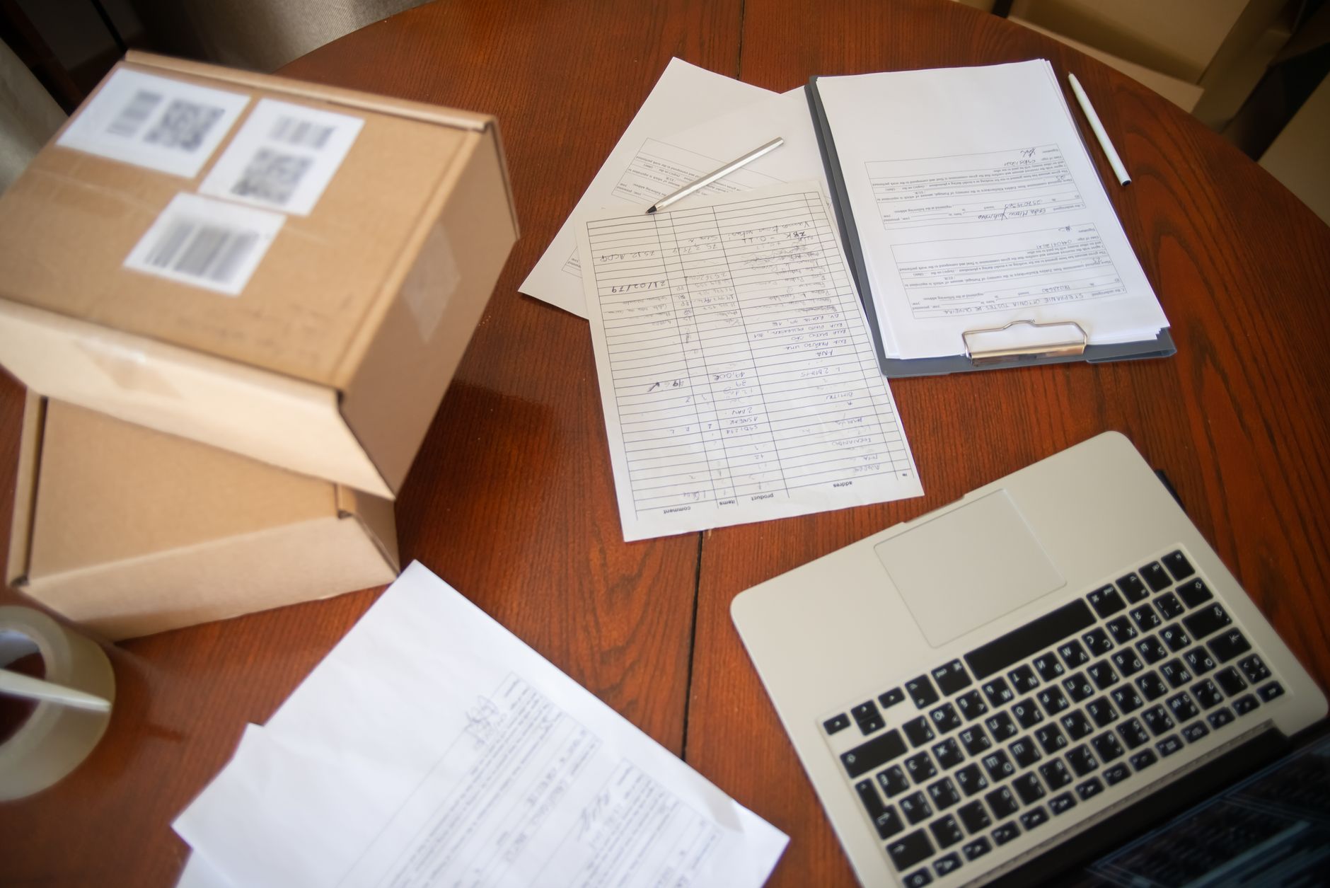 Werkplek met laptop, documenten en dozen voor e-commerce operaties.