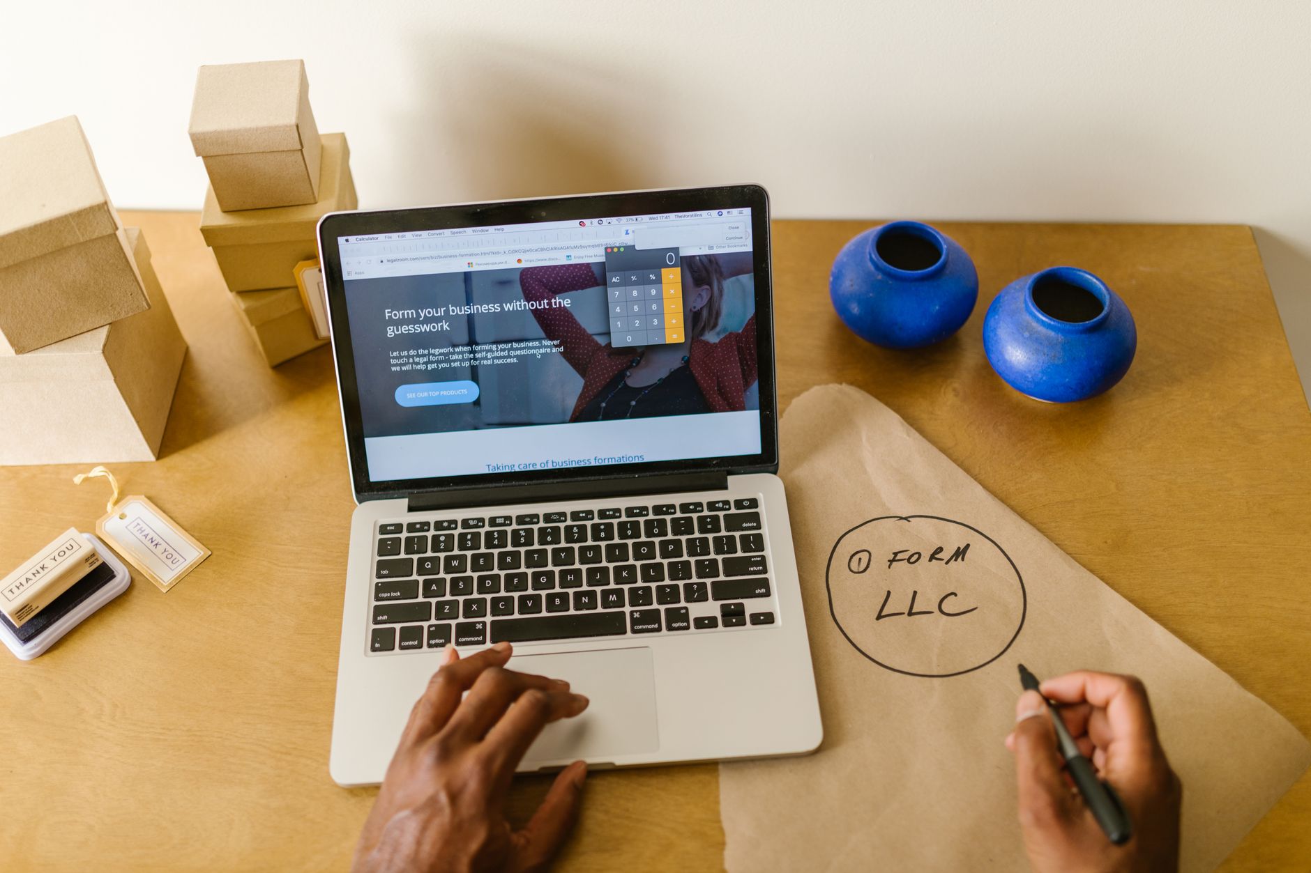 Werkplek met laptop, verpakking en handgeschreven aantekeningen voor een klein bedrijf.